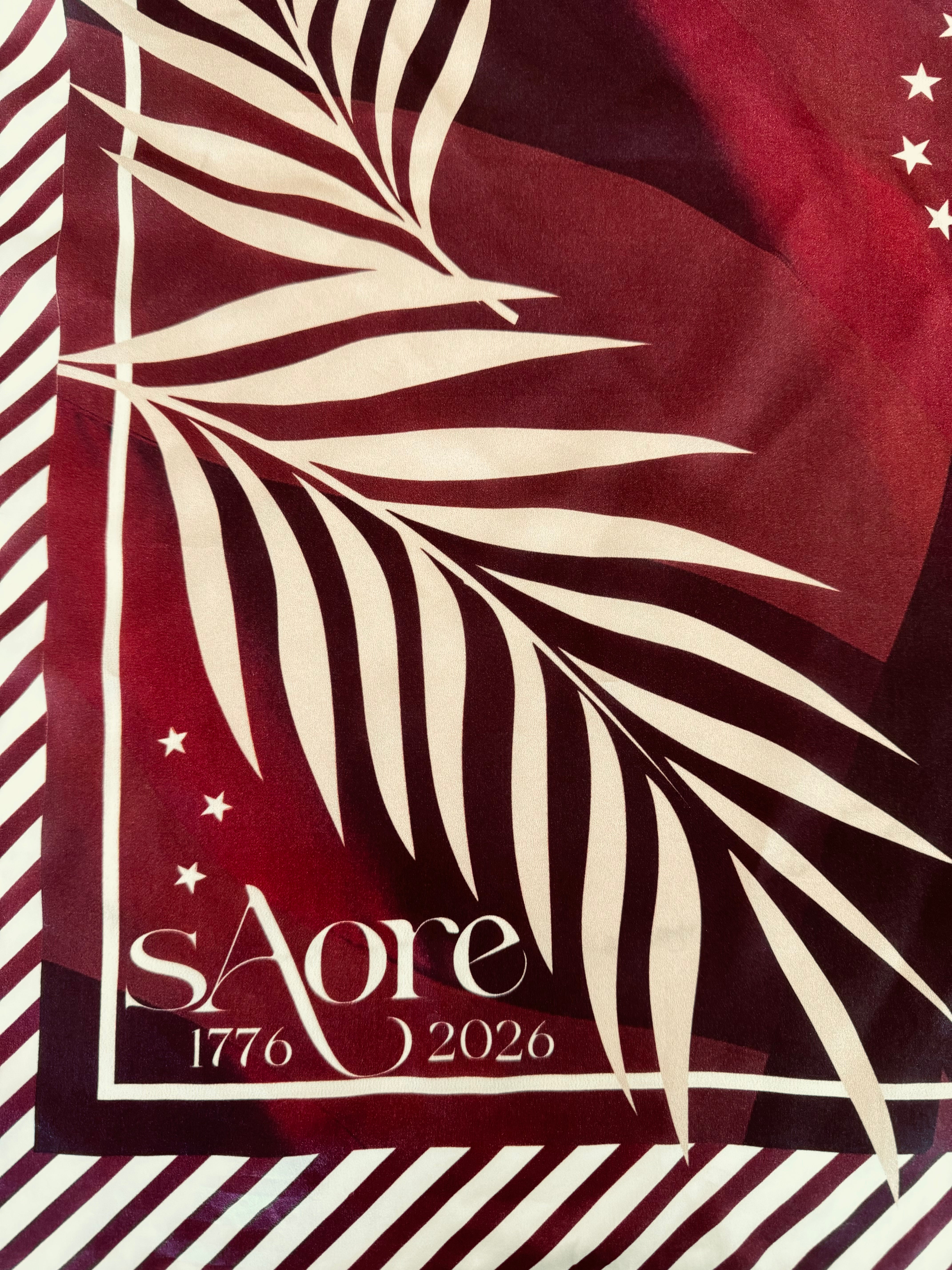 Fabric with palm leaf design and 'sáore' branding on a red and white striped background